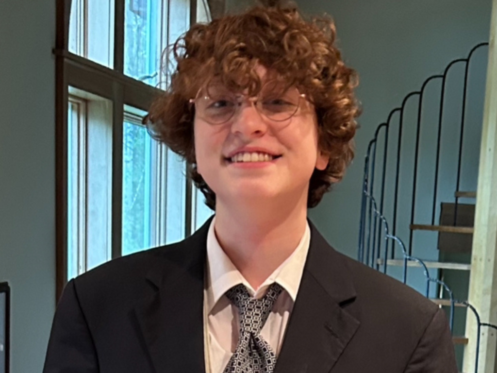 male student in suit and tie smiling