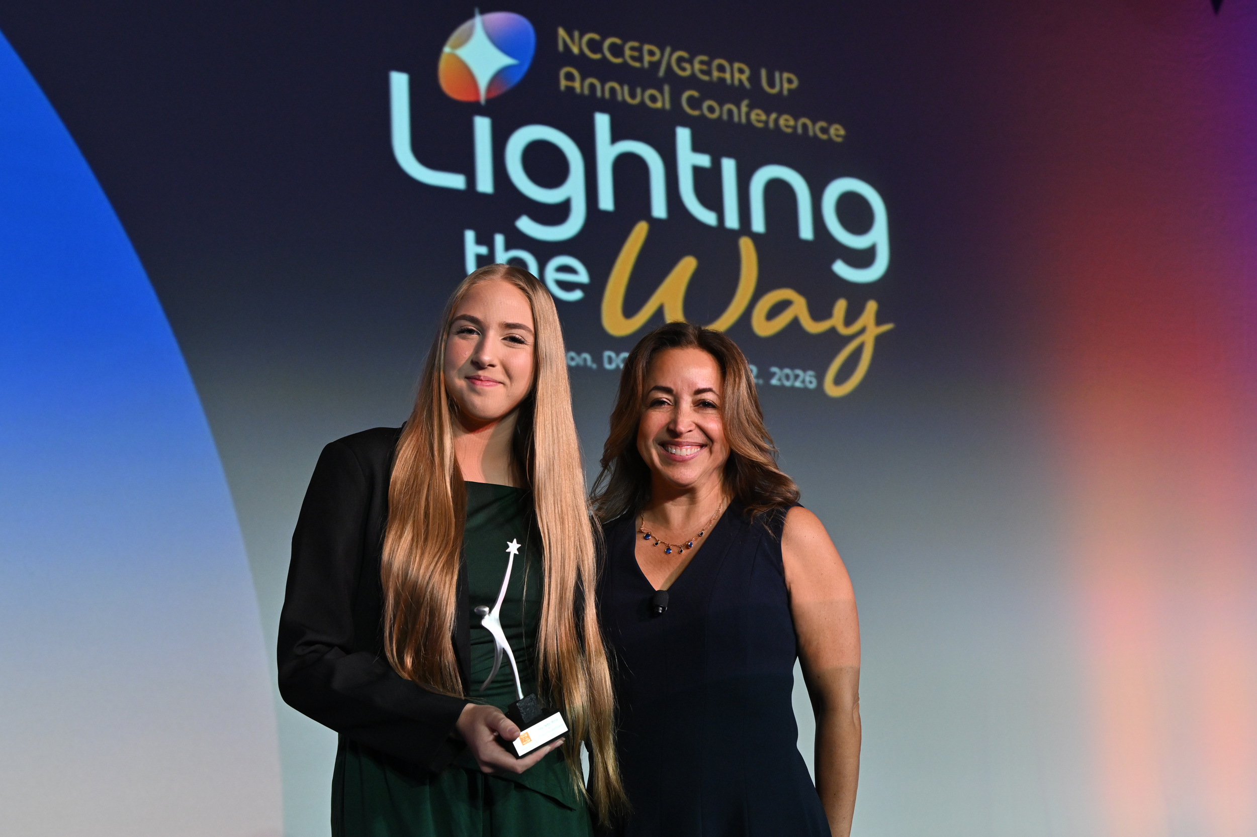 Two women stand with a glass award.