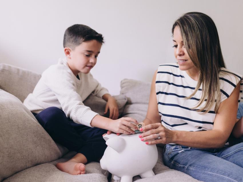 mother and son putting money in a piggy bank to save for education