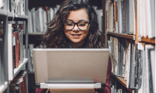 Student on computer in library stacks